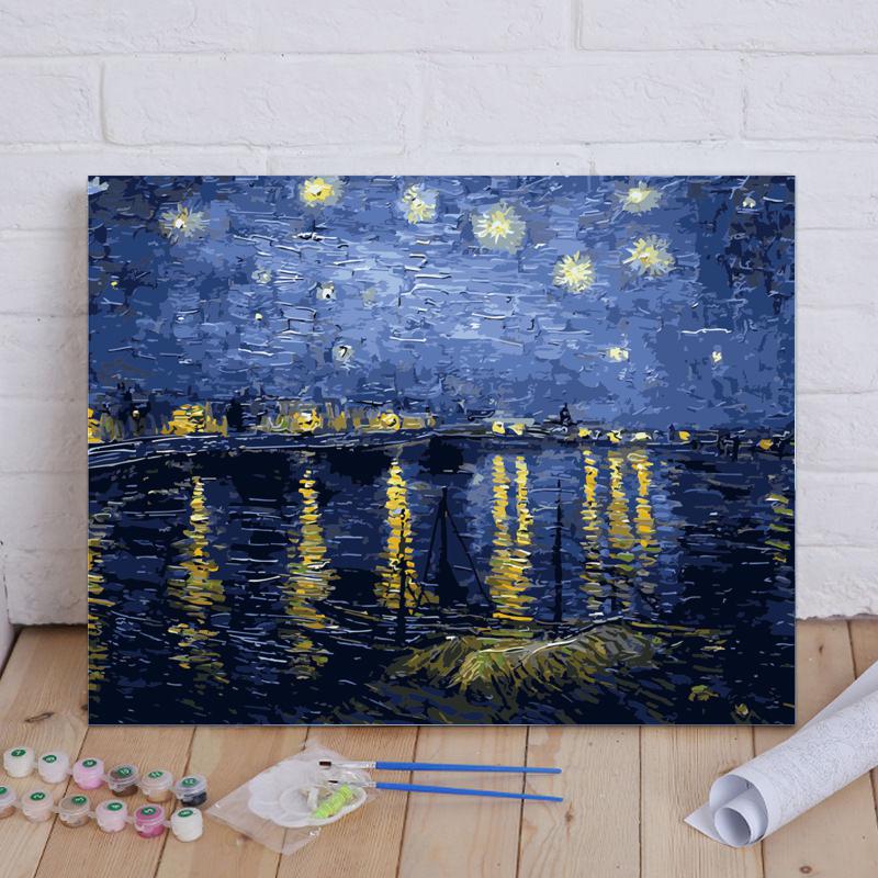 Painting of a night scene with lights reflected in water, placed on a wooden floor with art supplies.