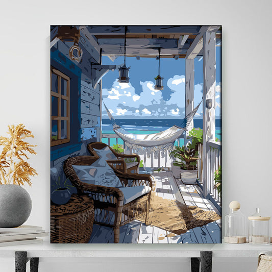 Framed artwork of a coastal scene with chairs and a hammock.