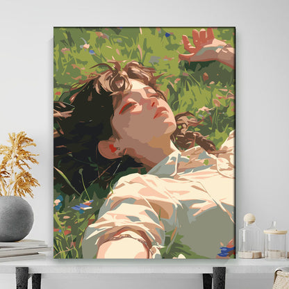 Framed artwork of a woman lying among flowers on a white wall.