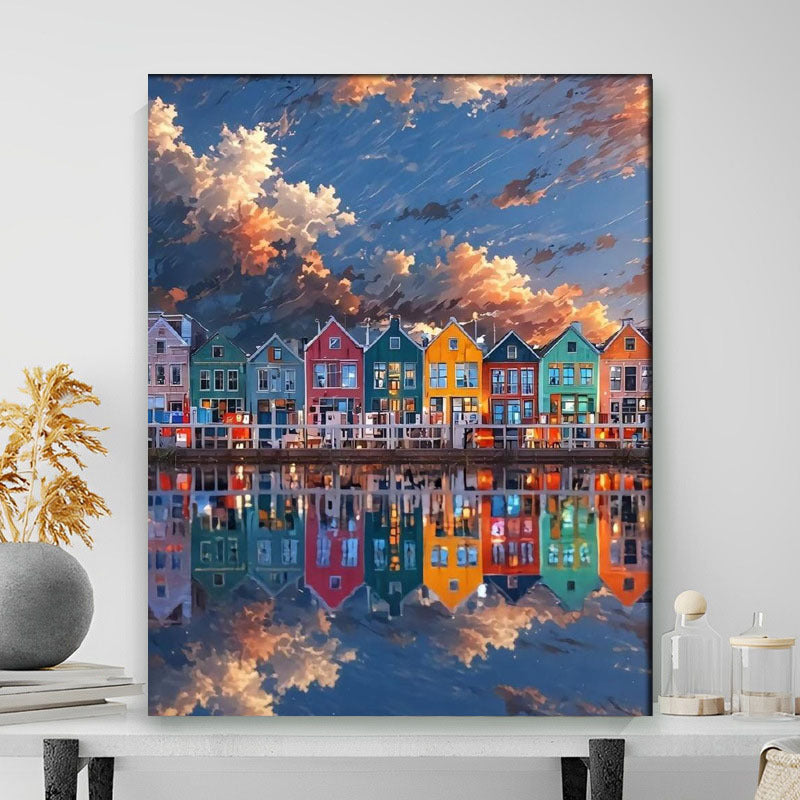 Framed artwork of colorful houses reflected in water with a blue sky.