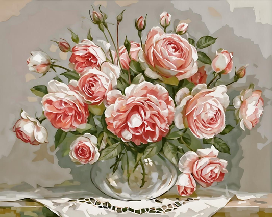 Bouquet of pink and white roses in a clear vase on a decorative tablecloth.