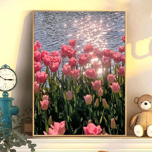 Framed artwork of pink tulips by a body of water with fireworks, displayed on a shelf.