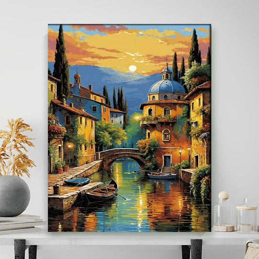 Painting of a picturesque Italian town with boats on a canal, set against a colorful sunset sky.