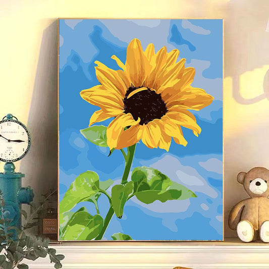 Painting of a sunflower on a blue background with decorative items around.