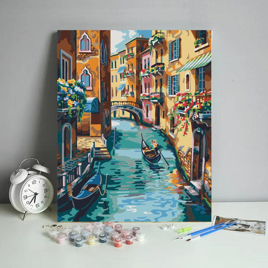 Painting of a Venetian canal with gondolas, surrounded by art supplies on a white surface.